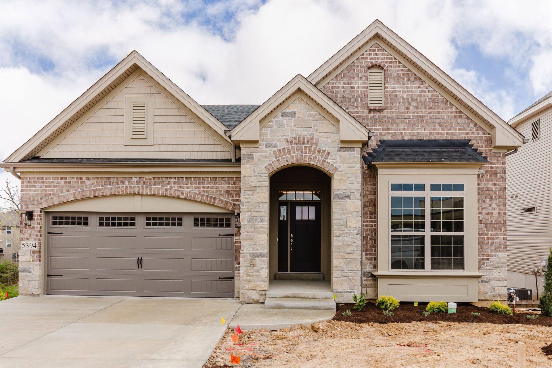 Exterior photo of the Marilyn Monroe model with arched entry and window, gray garage door.