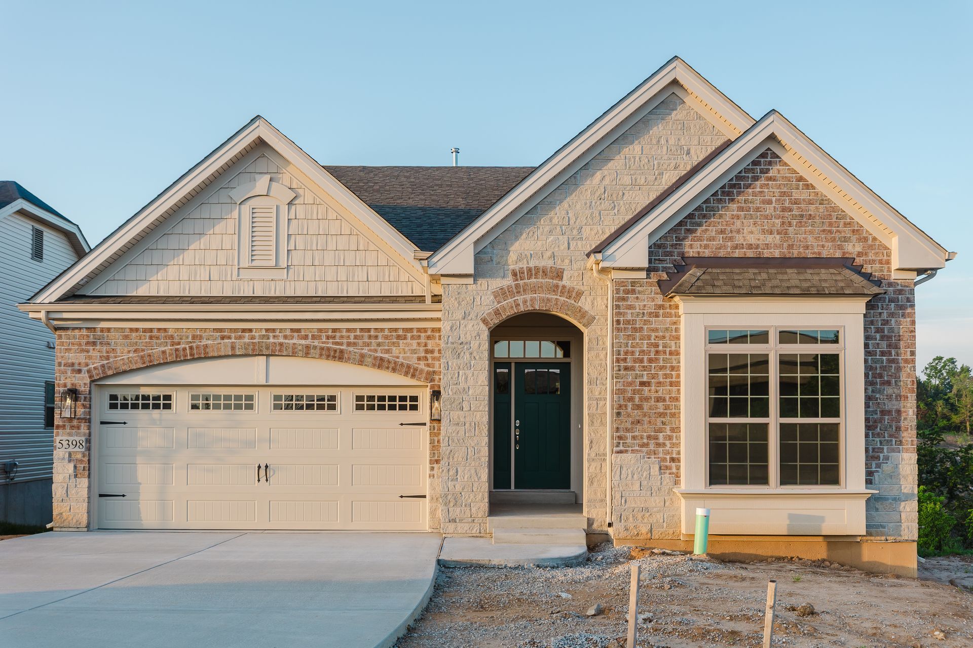 Exterior image of the Dean Martin model with a two-car garage, window, and arched doorway.