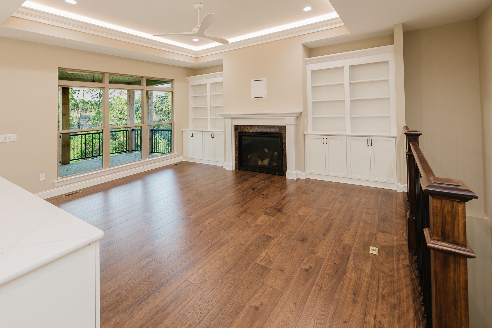 Living room of the Dean Martin model with fireplace, built-in bookshelves, and hardwood floors.