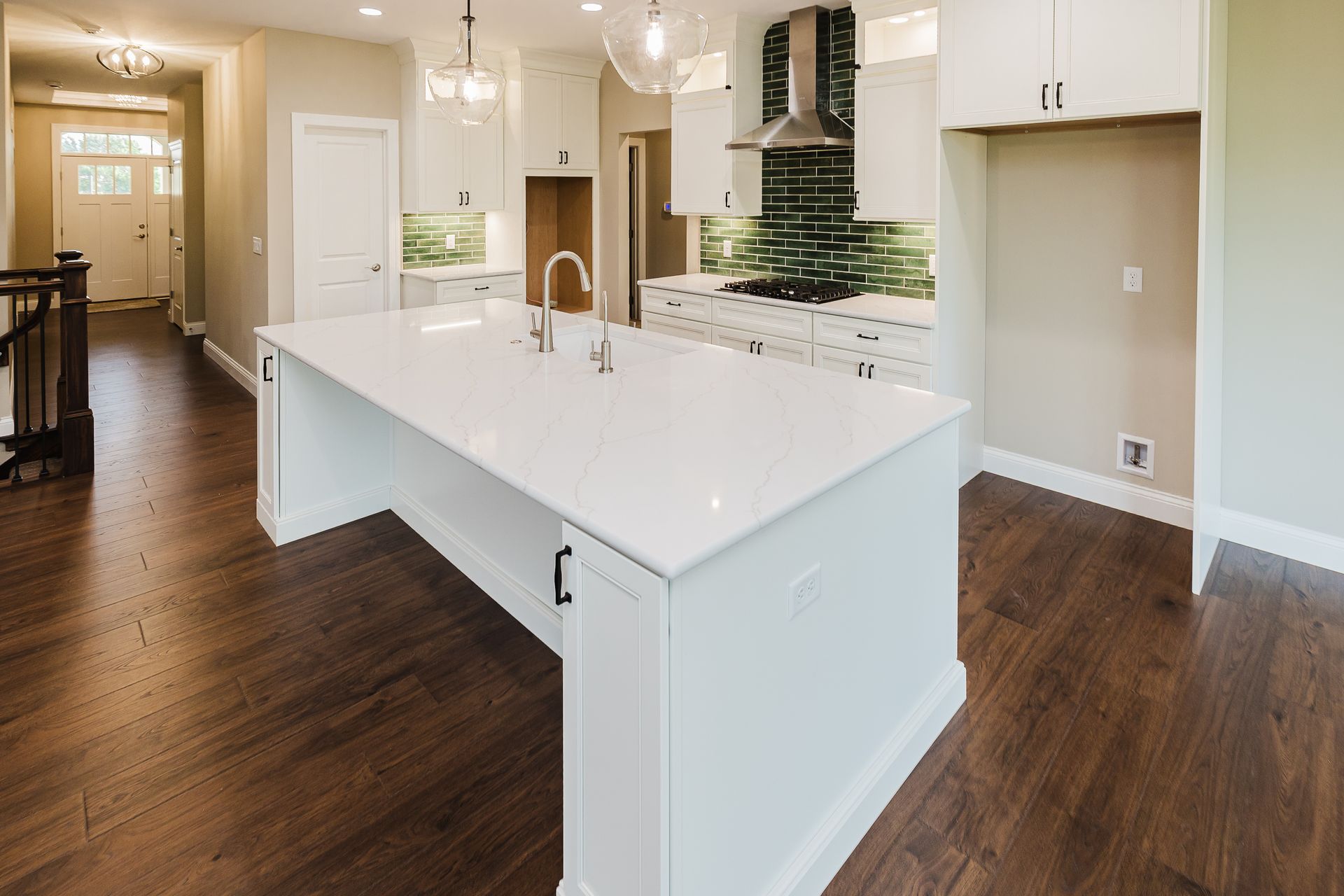 Kitchen of the Dean Martin model with white cabinets, large island, and dark wood floors.