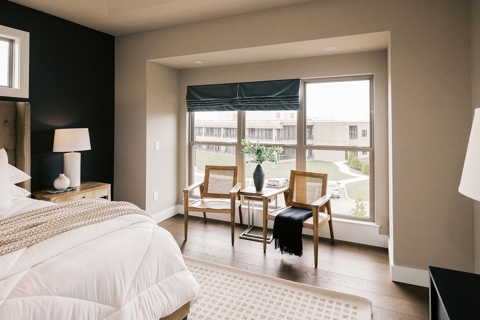 Bedroom in the Cary Grant model with bed, chairs by window, and dark accent wall.