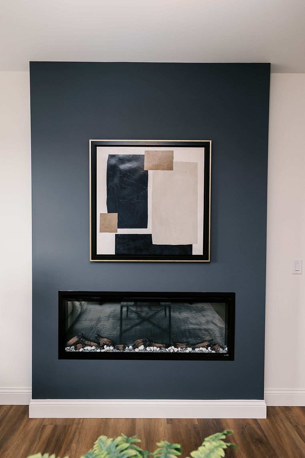 Navy blue accent wall in the Cary Grant model with fireplace and abstract art.