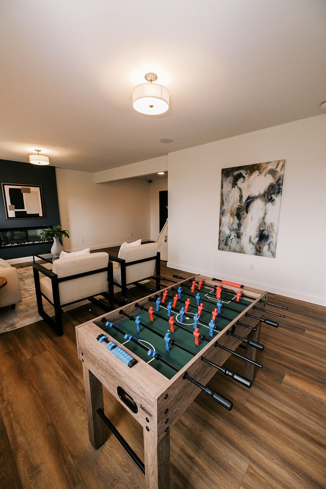 Foosball table in the Cary Grant model a modern living room with a painting and seating.