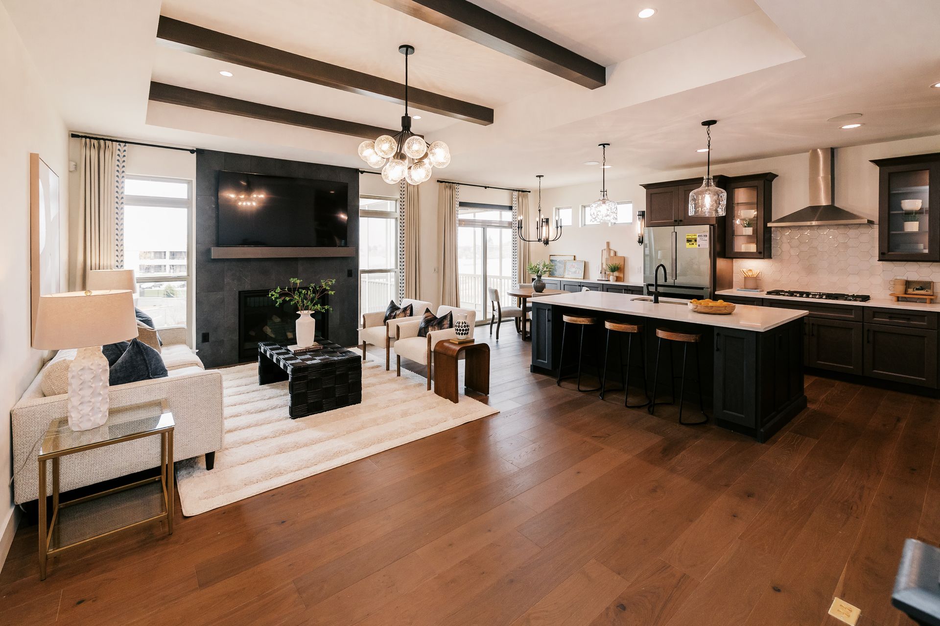Modern living room in the Cary Grant model with kitchen, dark wood cabinets, and seating area with fireplace.