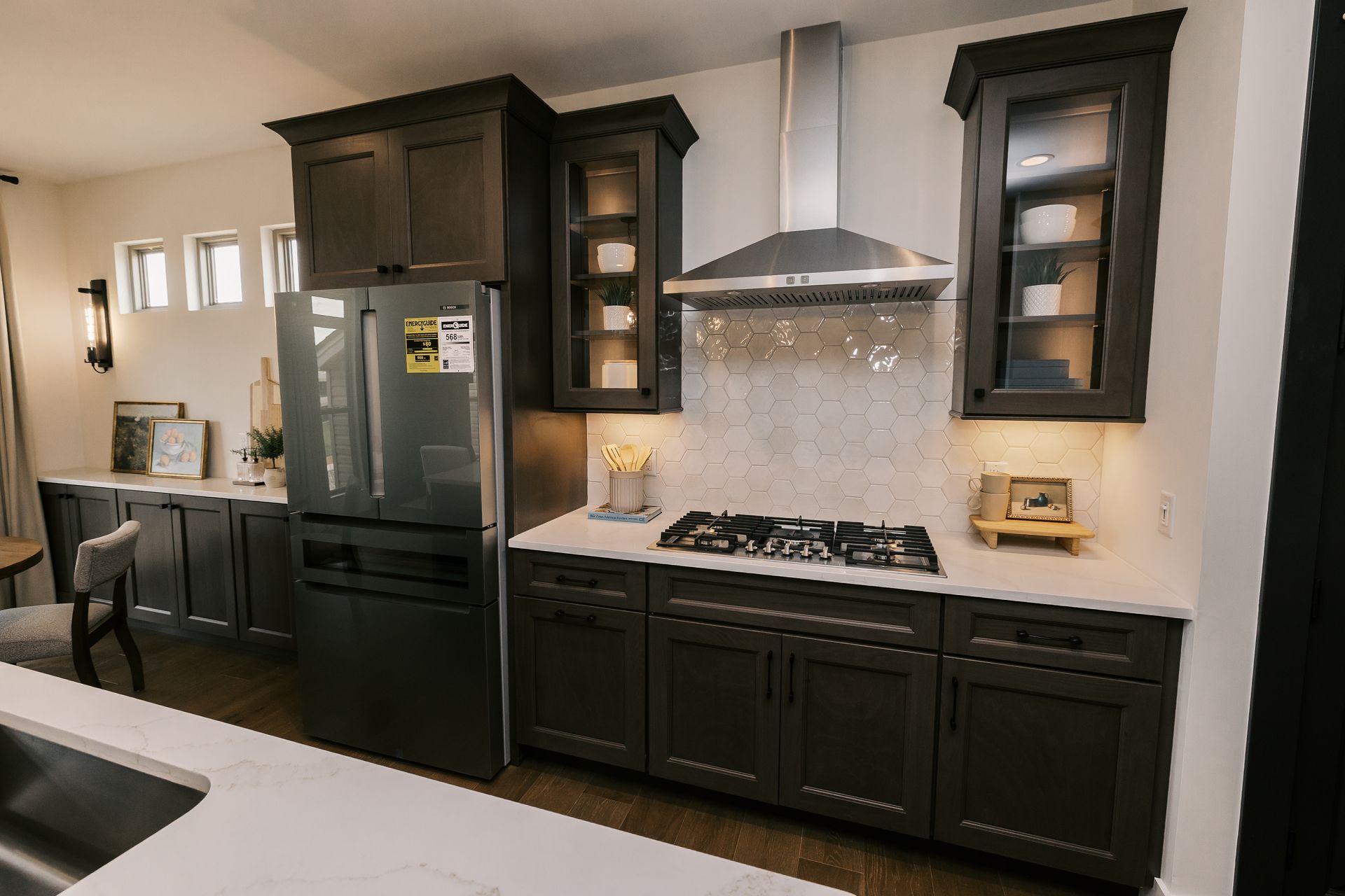Dark cabinets in the Cary Grant model kitchen, stainless steel appliances, and white countertops.