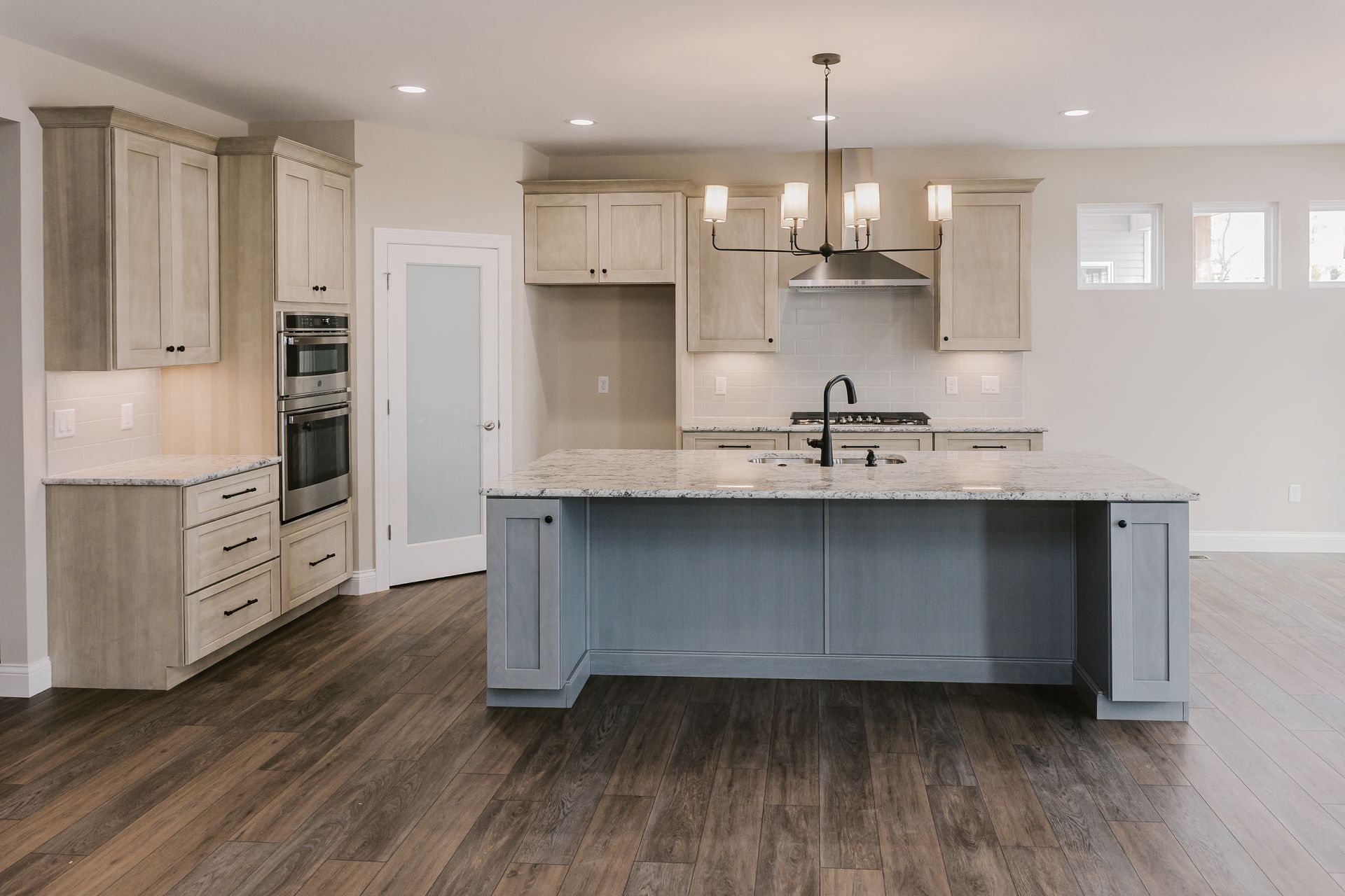 Kitchen of the Marilyn Monroe model with wood cabinets, blue island, granite countertops, and hardwood floor.