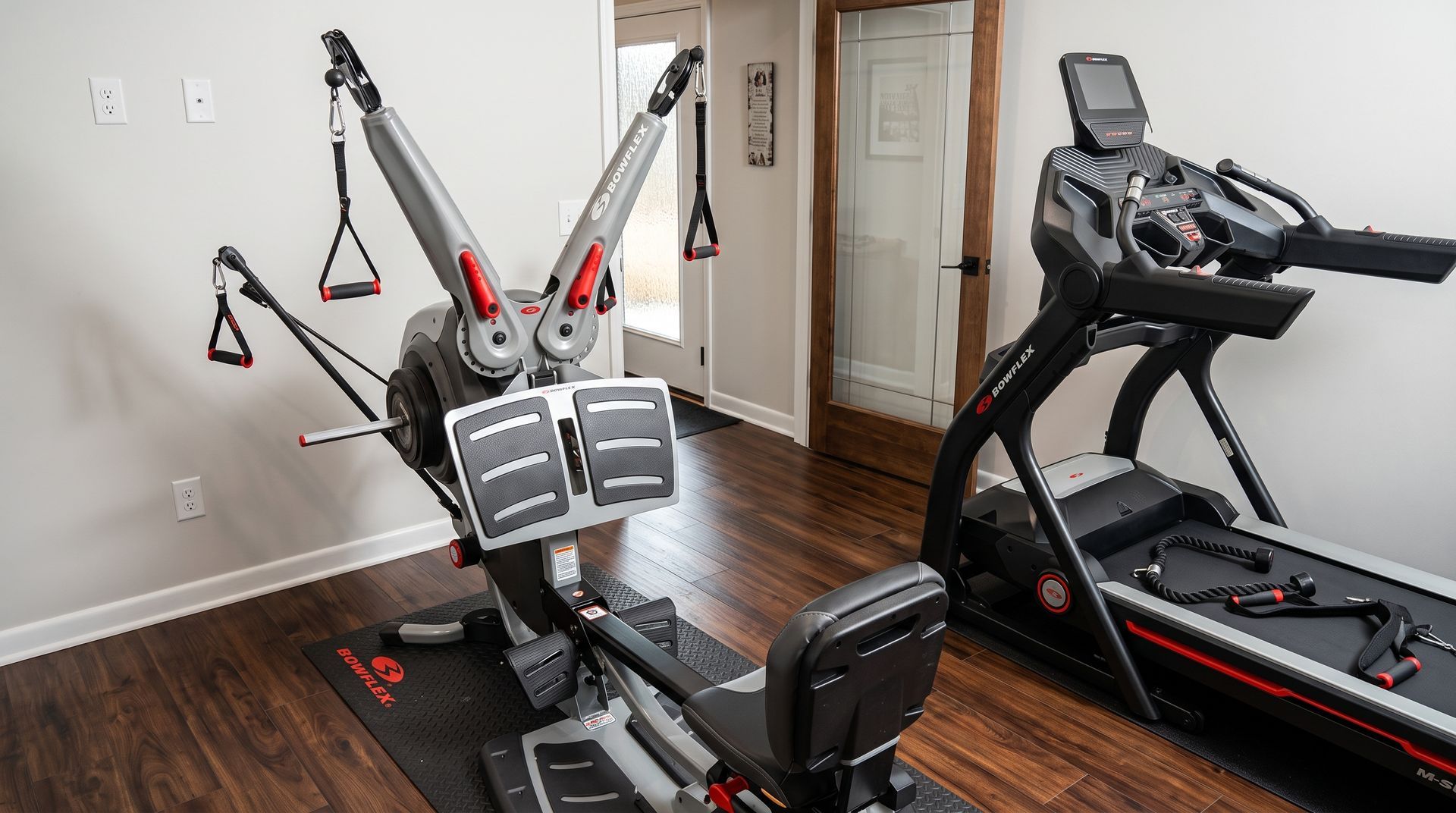 Home gym with an elliptical machine and a treadmill on hardwood floors.