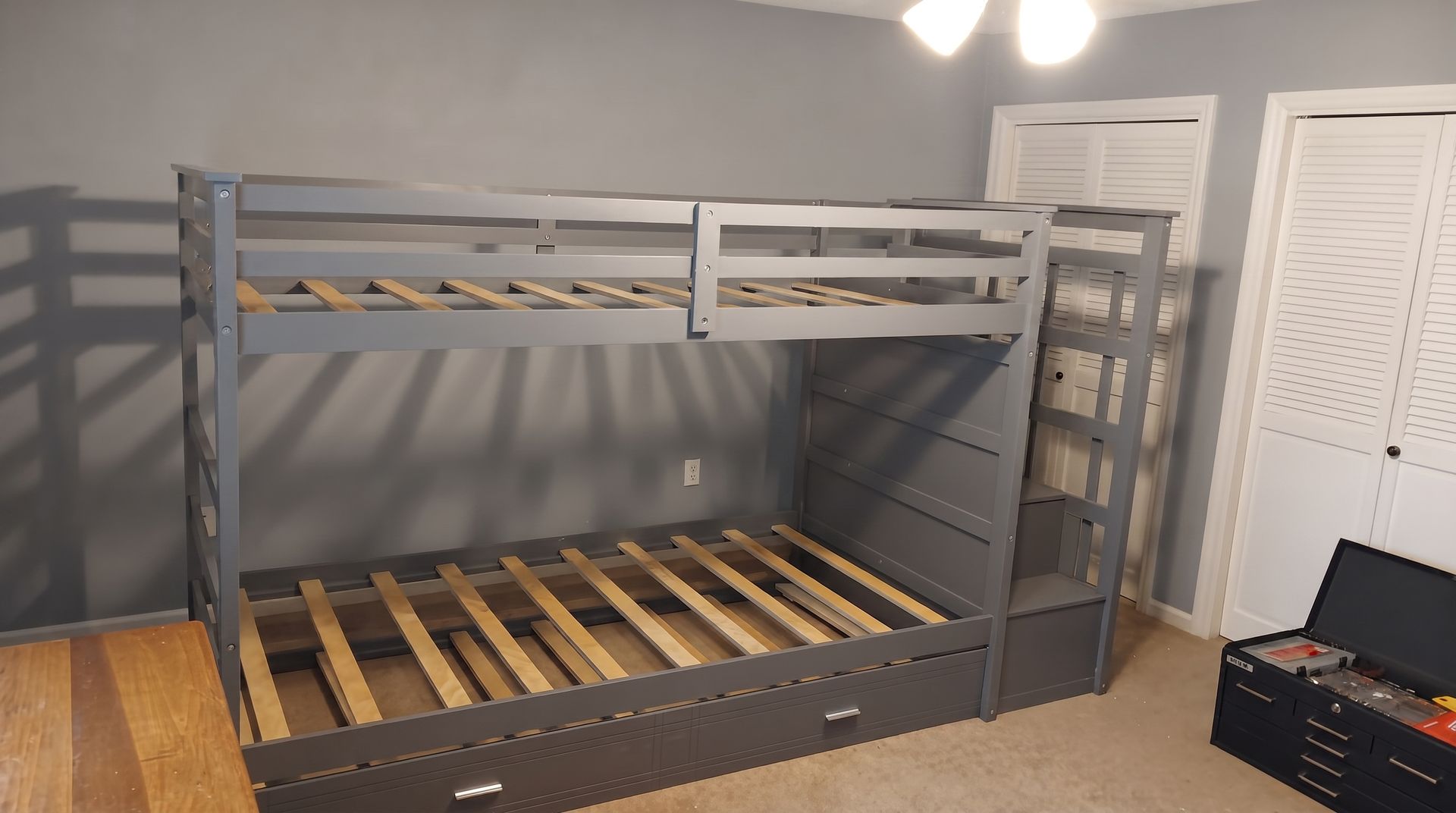 Gray wooden bunk bed frame with slatted lower bed in a bedroom