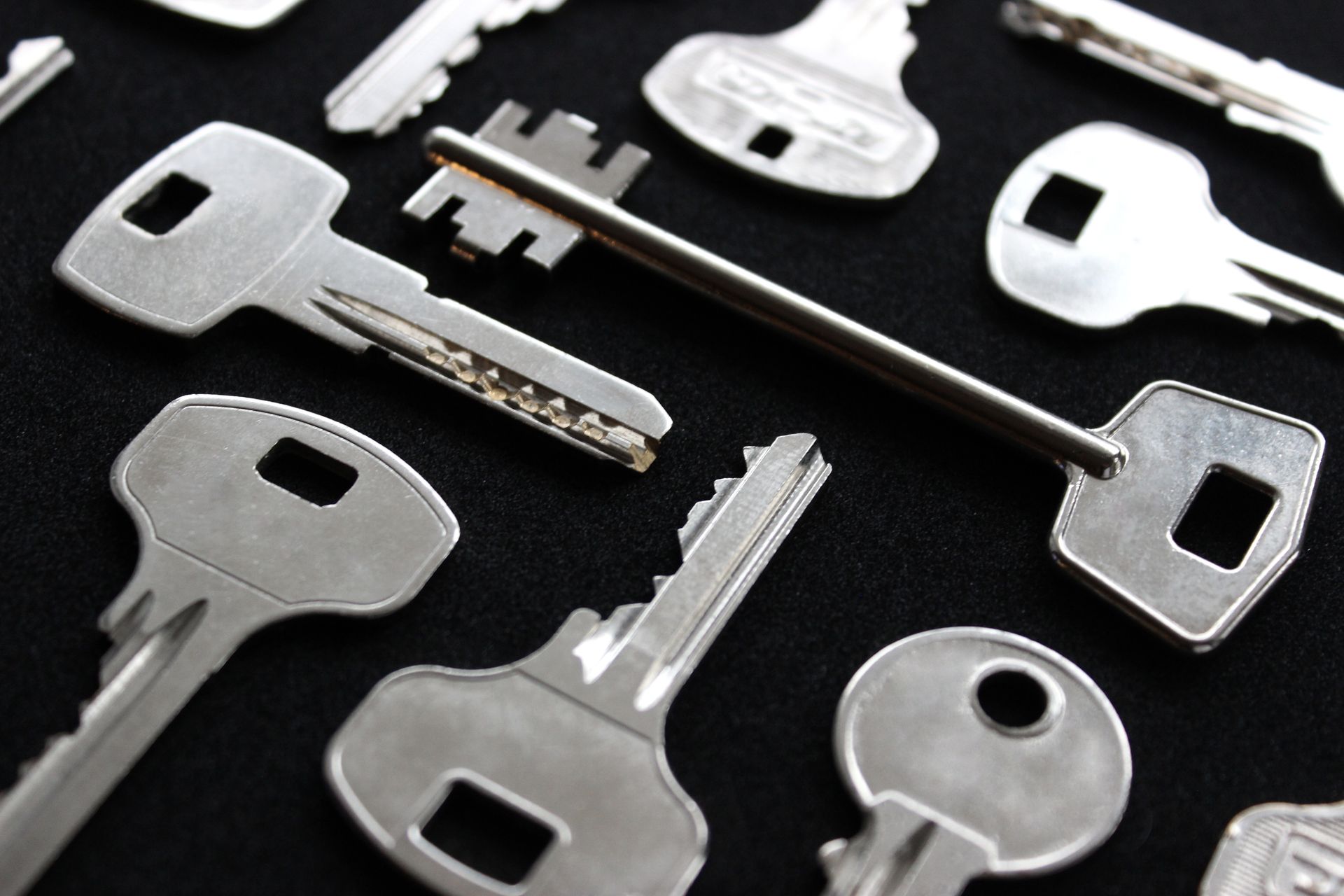 Assorted silver metal keys scattered on a black surface
