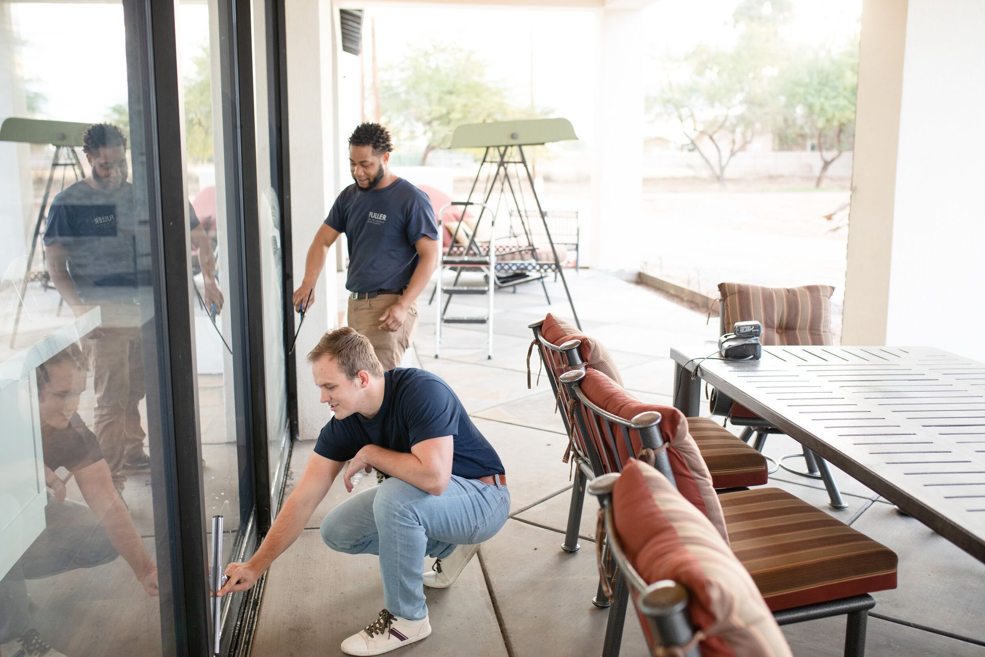 Two workers cleaning a bright outdoor patio with tables and chairs
