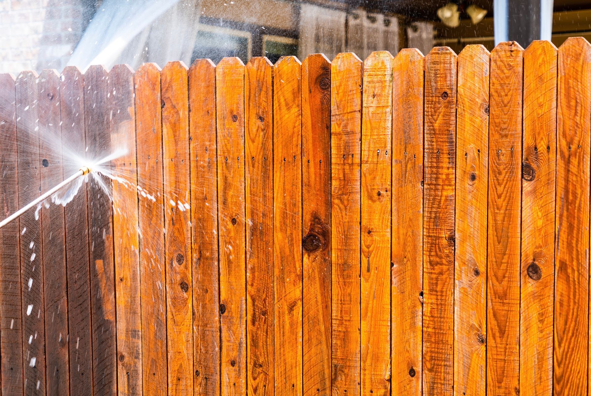 Water spraying onto a weathered orange wooden fence, creating a bright splash on the left.