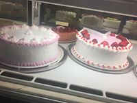 Two cakes are sitting on a display case in a bakery