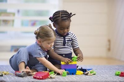 Two children playing with colorful blocks on a carpeted floor