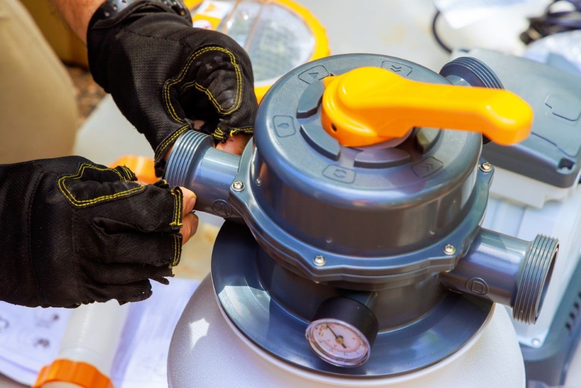 Gloved hands adjusting a gas cylinder valve with a yellow handle and pressure gauge