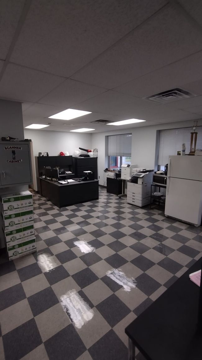 Office room with checkered floor, desks, cabinets, and fluorescent ceiling lights