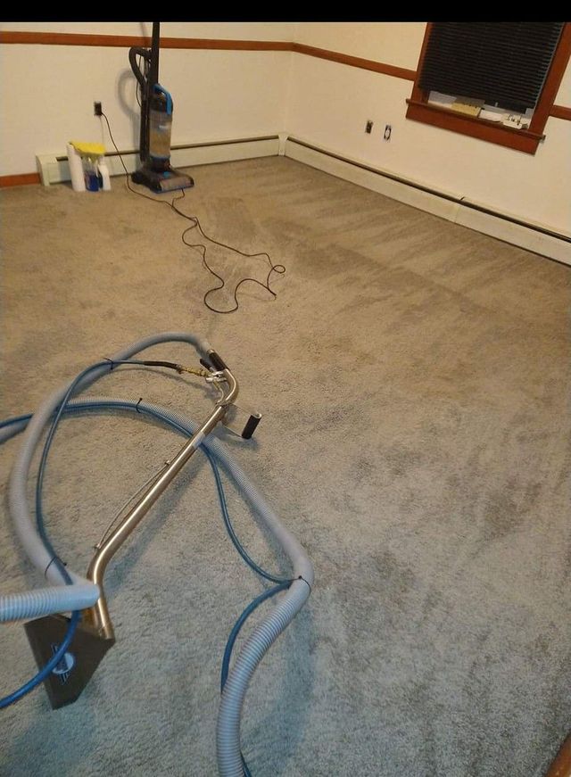 Carpet cleaning machine and hoses on a beige carpet in an empty room