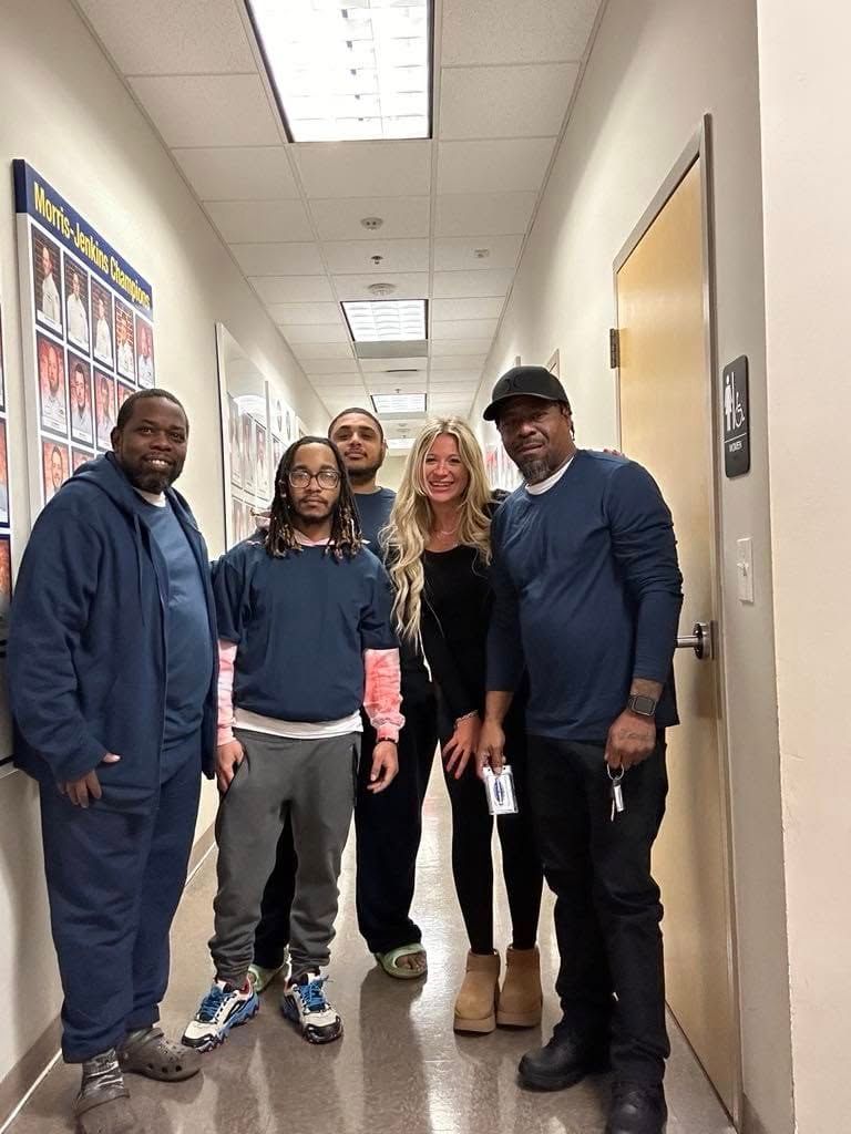 Four people standing in a hallway, smiling at the camera.
