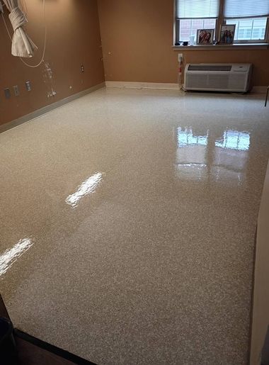 Empty room with tan walls, speckled floor, and a window air conditioner under a window.