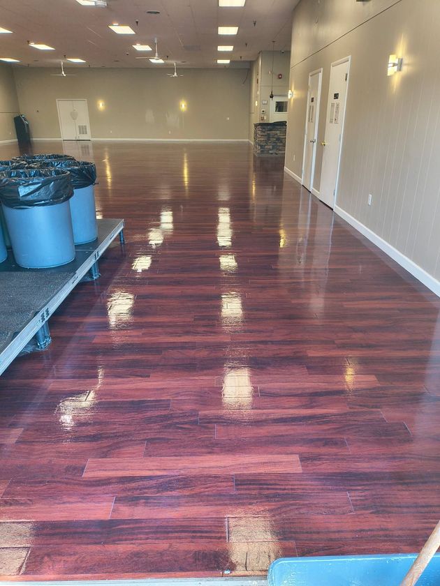 Empty room with glossy red wood floor, white walls, and overhead lights