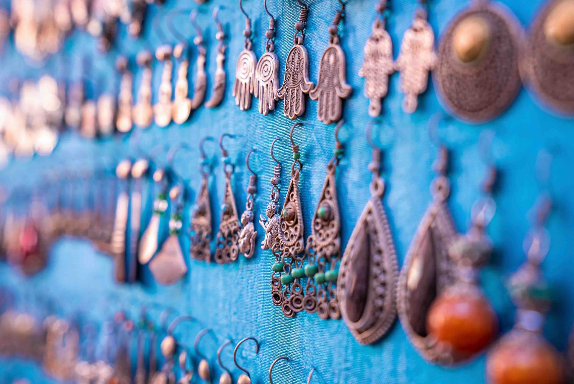 a bunch of earrings are hanging on a blue wall .
