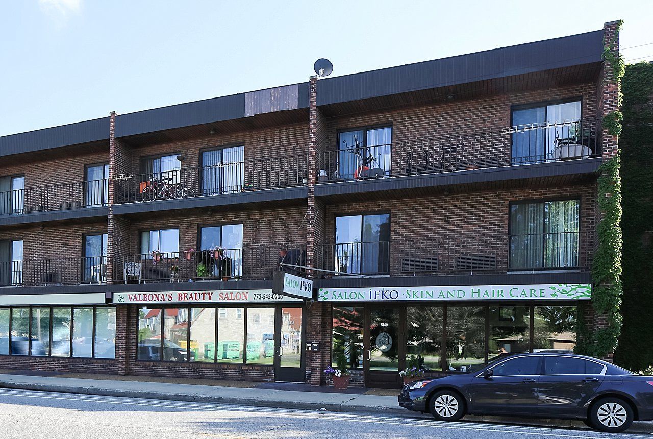 A car is parked in front of a large apartment building.