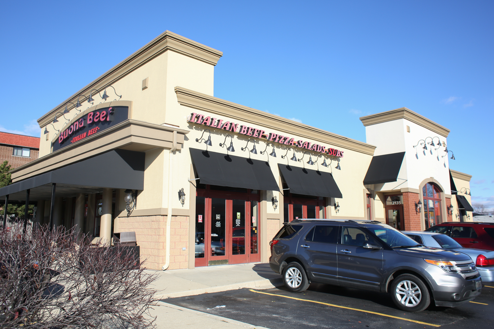 A car is parked in front of a pizza restaurant