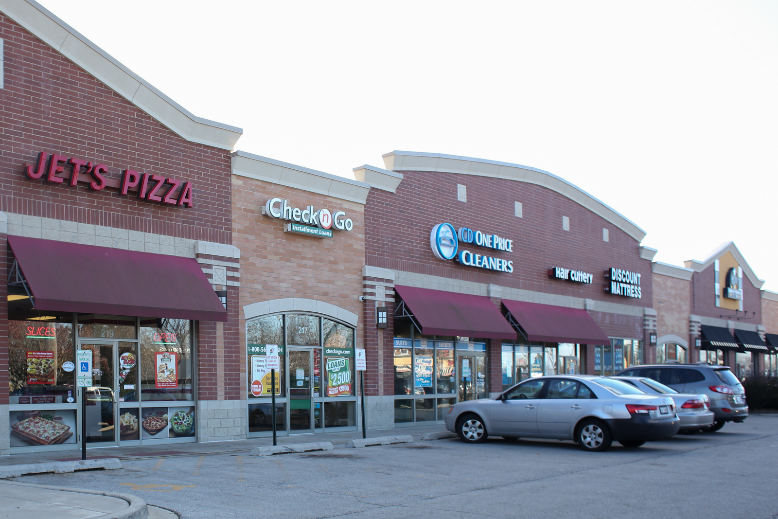 Cars are parked in front of a jets pizza restaurant