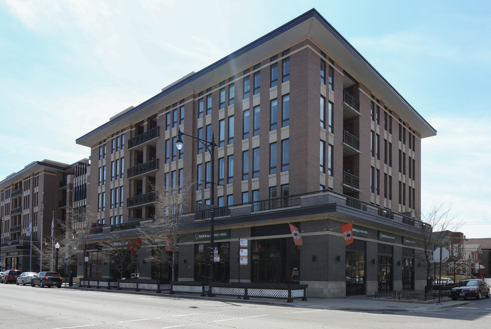 A large brick building with a lot of windows is on the corner of a street.