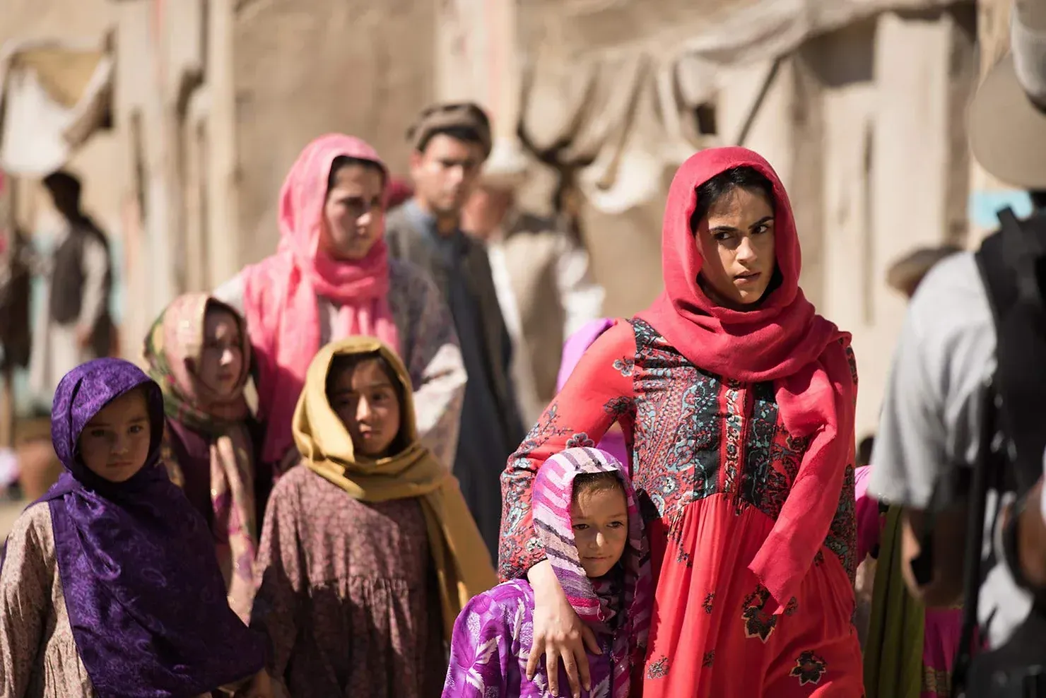 A woman in a red dress is standing in a crowd of people.