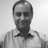 A man in a shirt is smiling in a black and white photo.