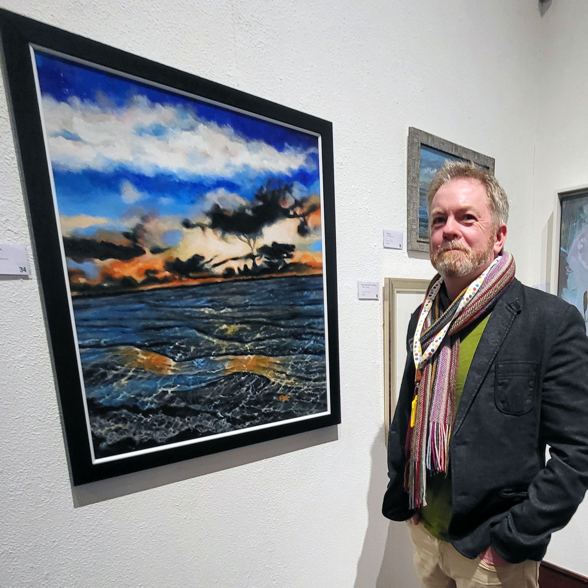 Artist Paul Trainor stands alongside his seascape