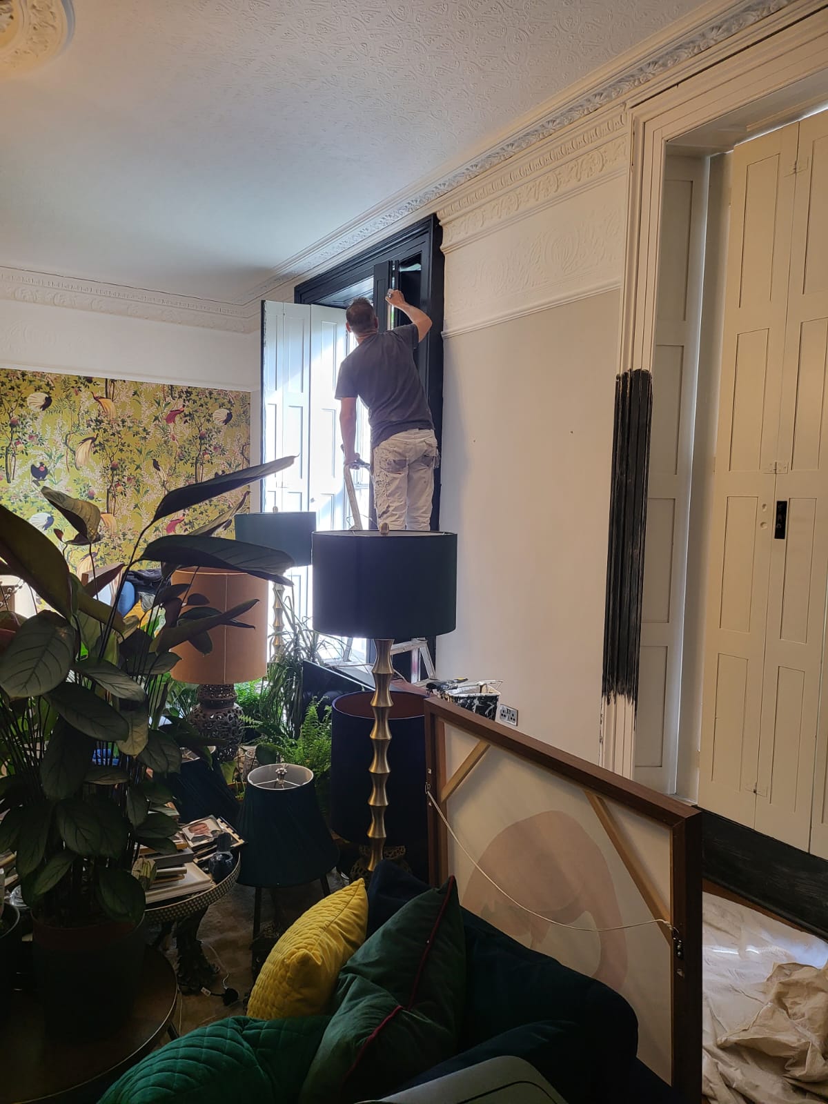picture of one of our painters and decorators in Derby painting a wooden window frame in dark grey