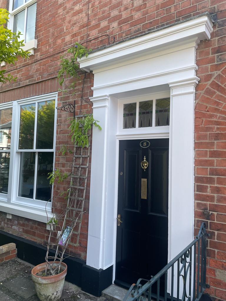 A picture of a front door and timber windows painted in white by painters and decorators Derby
