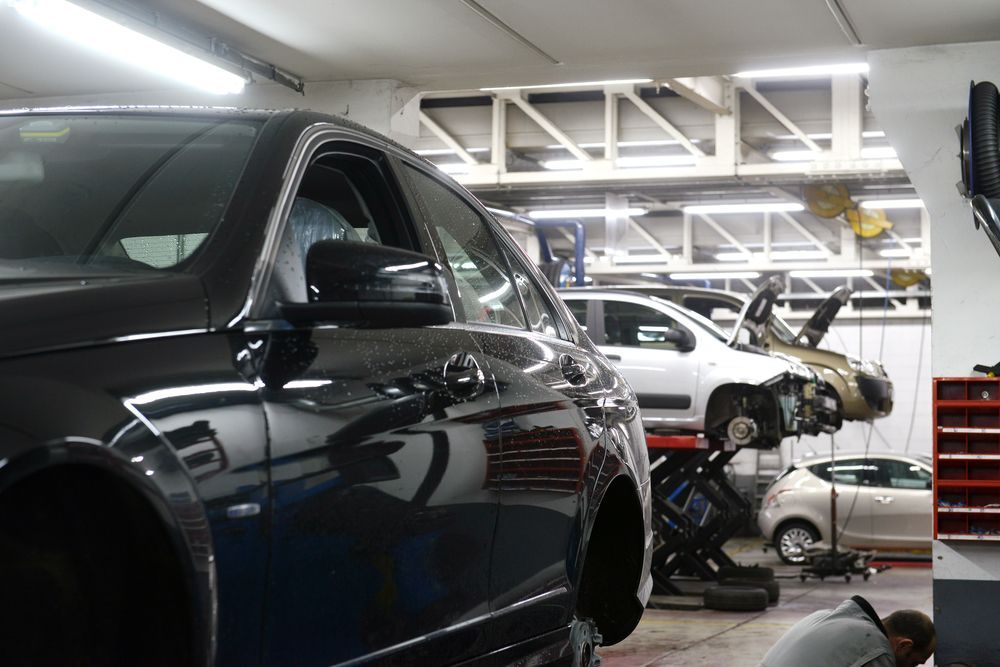 A Black Car is Parked in a Garage With Other Cars — Allan Ross Mechanical Repairs in Charmhaven, NSW