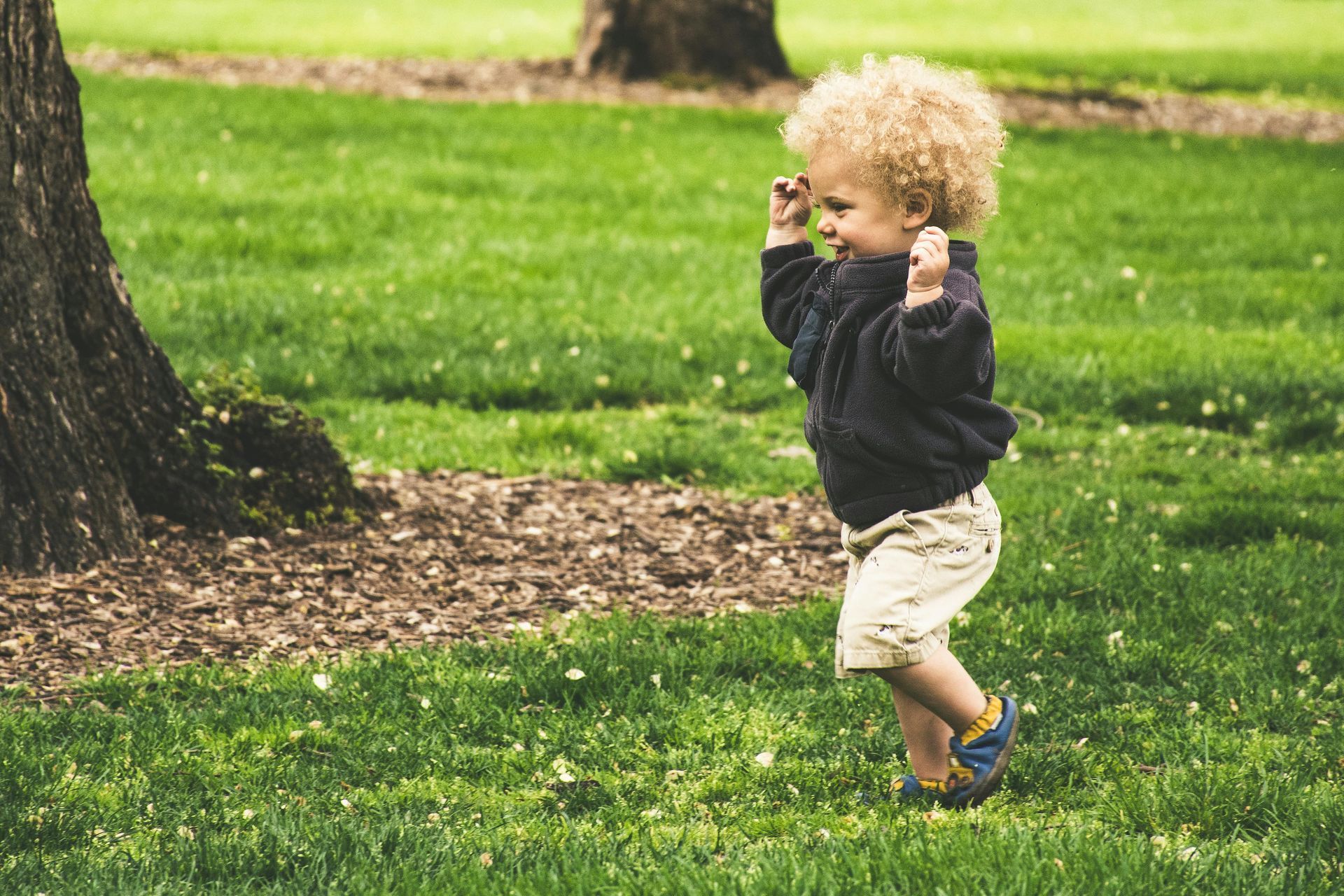 little boy playing outside by a tree
