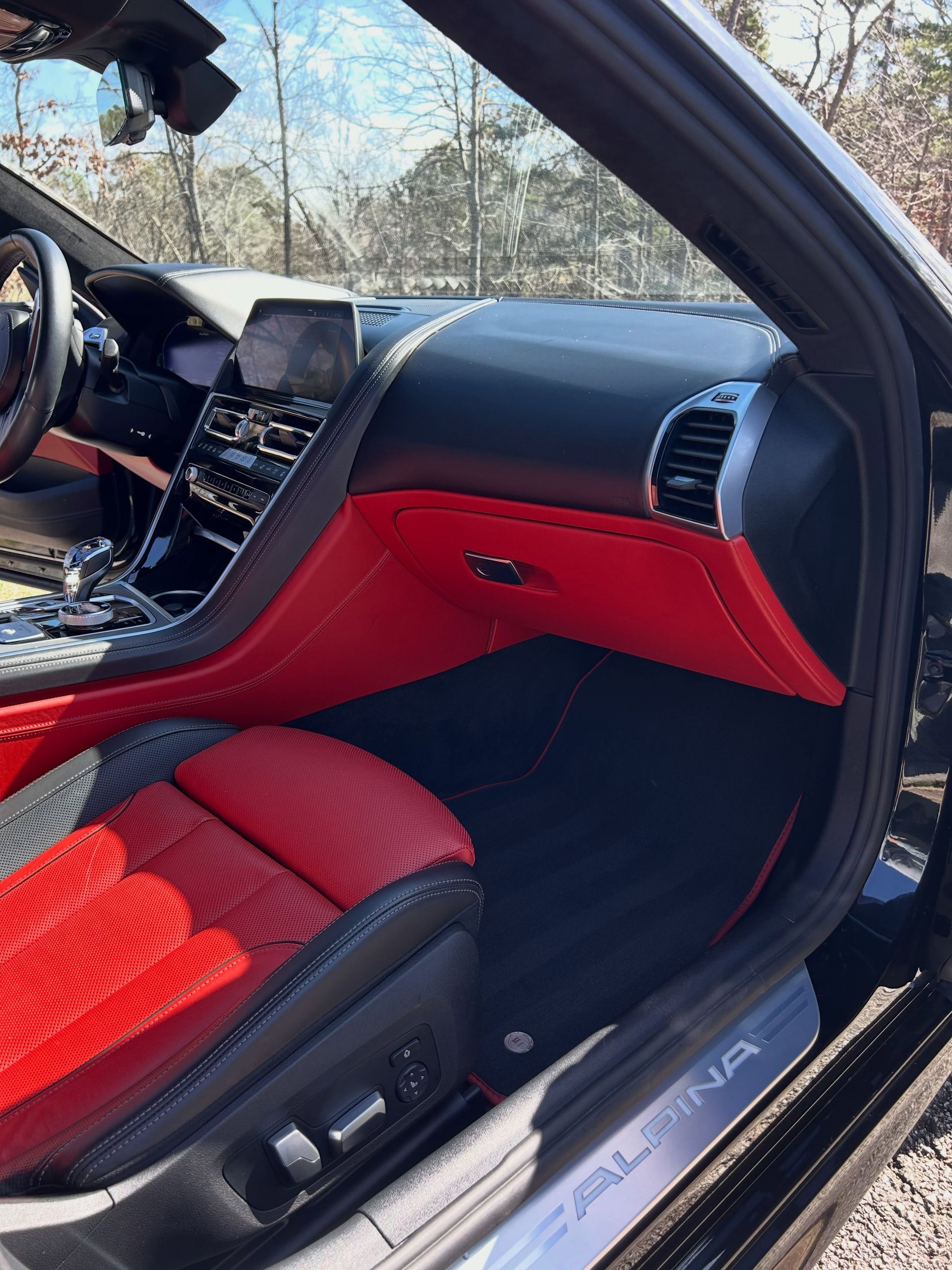 Red-and-black luxury car interior with dashboard and passenger seat visible