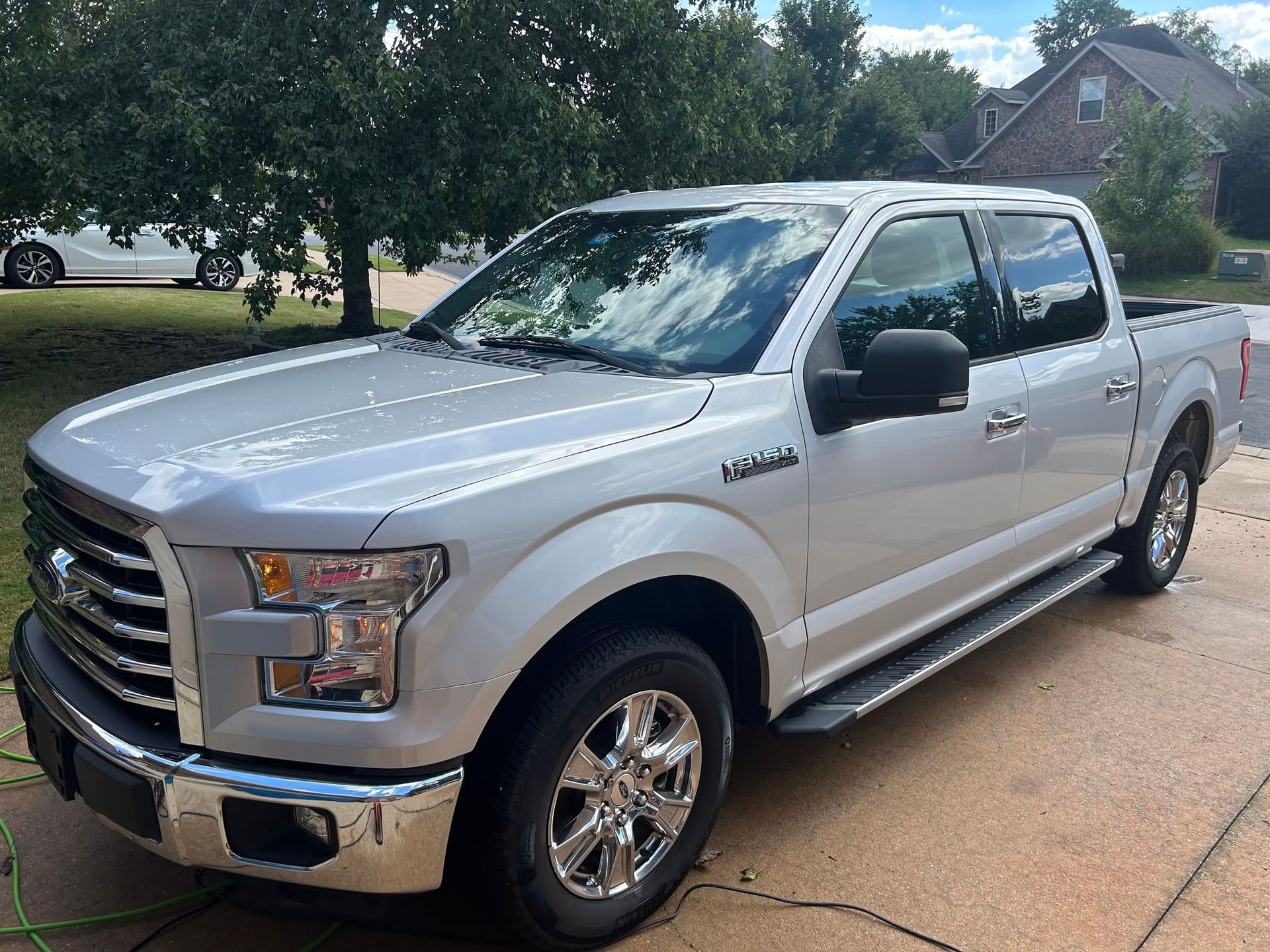 Silver pickup truck parked on a driveway beside a suburban street, front-left view