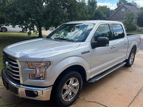 Silver Ford pickup truck parked in a driveway on a suburban street.