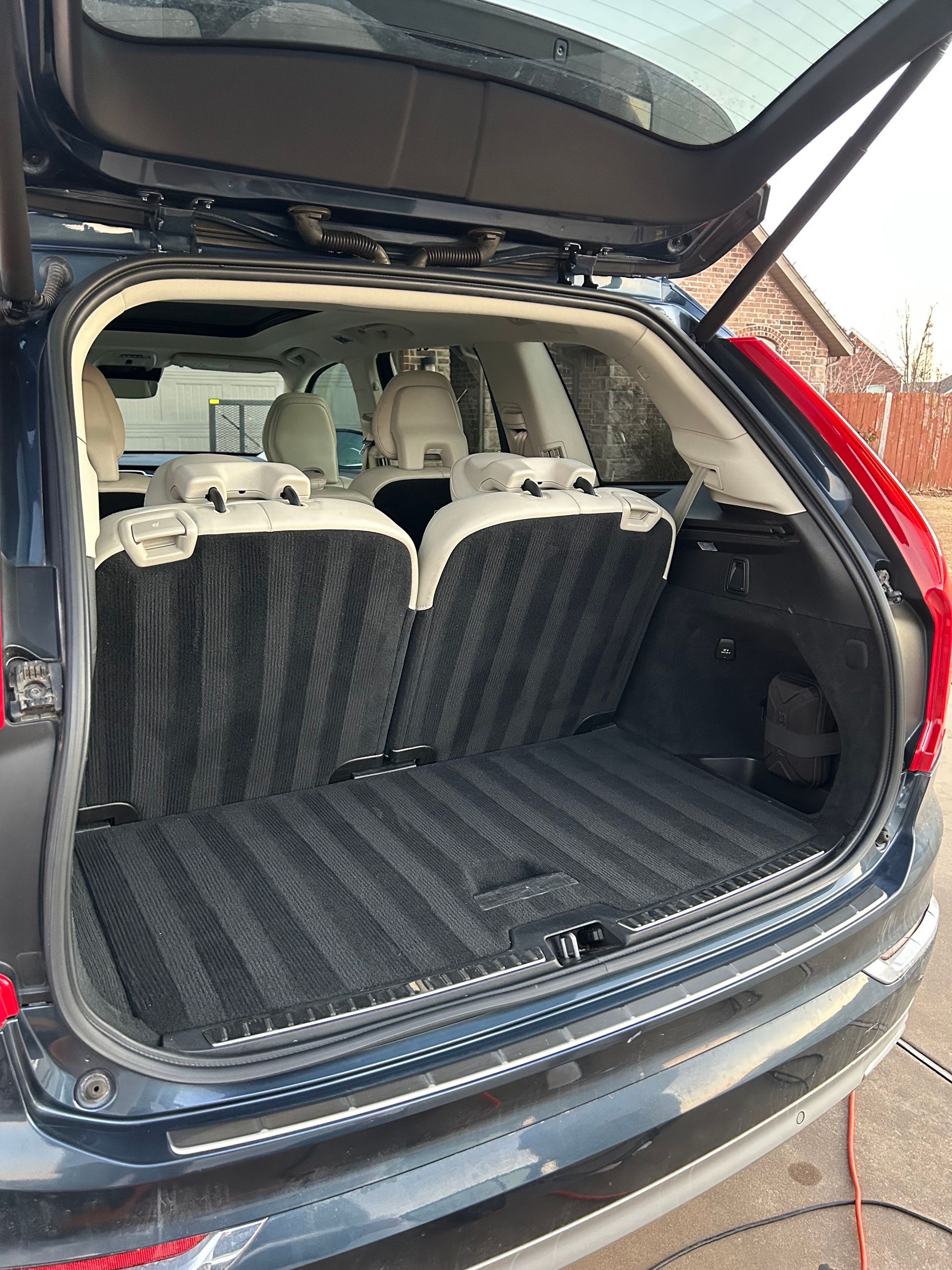 Open SUV cargo area with folded rear seats and black cargo mat in place