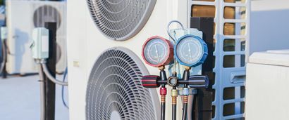 Manifold gauge set connected to an outdoor HVAC condenser unit on a rooftop.