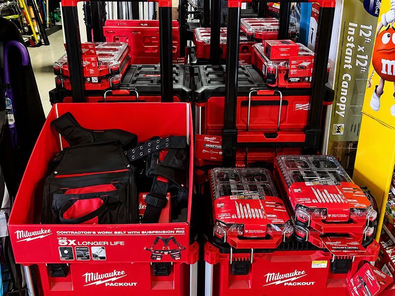 Milwaukee tool display with red toolboxes, batteries, and bags on store shelves