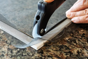 Hand using a drill to install a metal hinge on a door frame