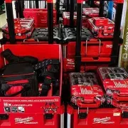 Milwaukee tool display with red toolboxes, batteries, and bags on store shelves