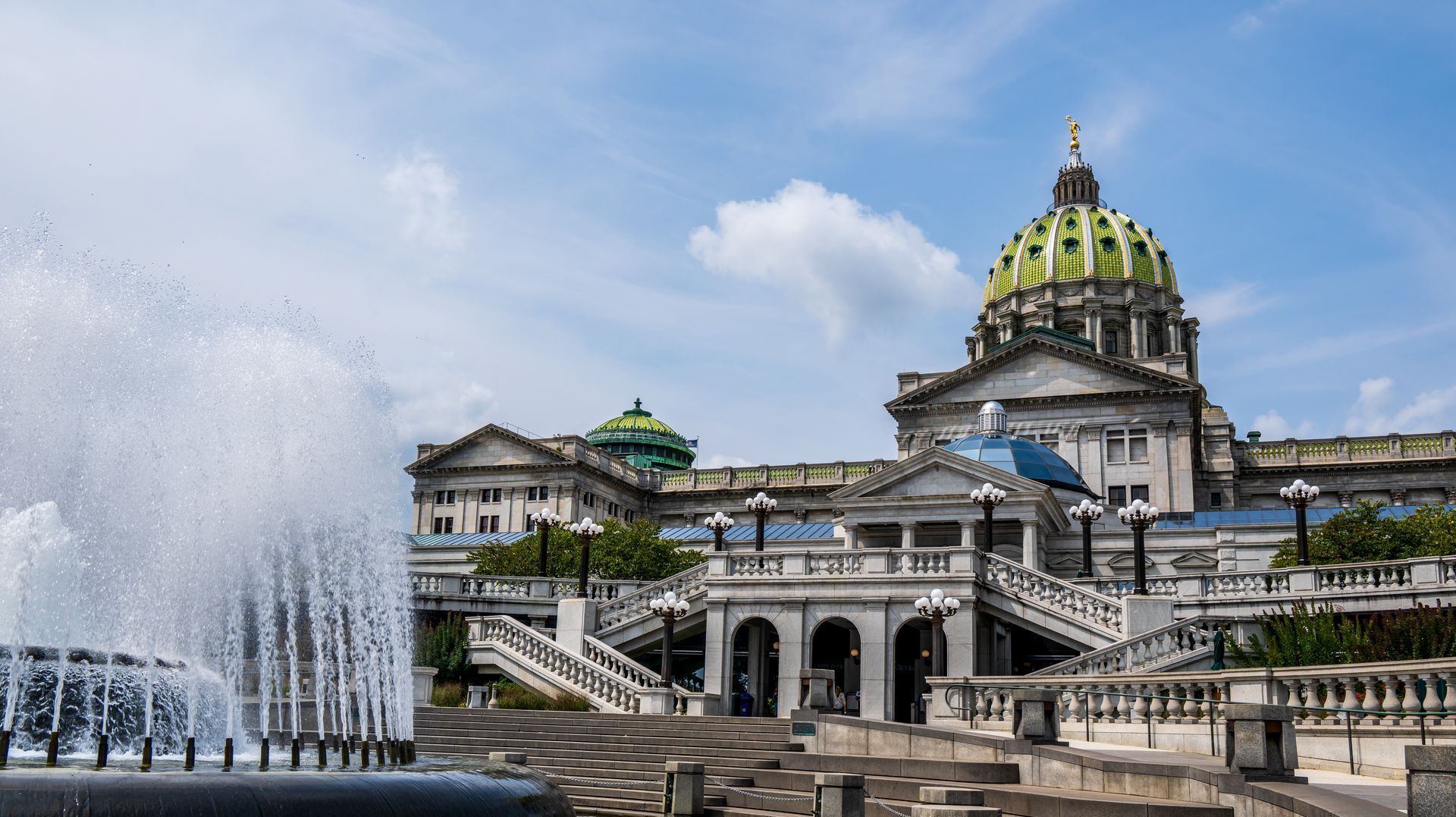 A fountain is spraying water in front of a large building.