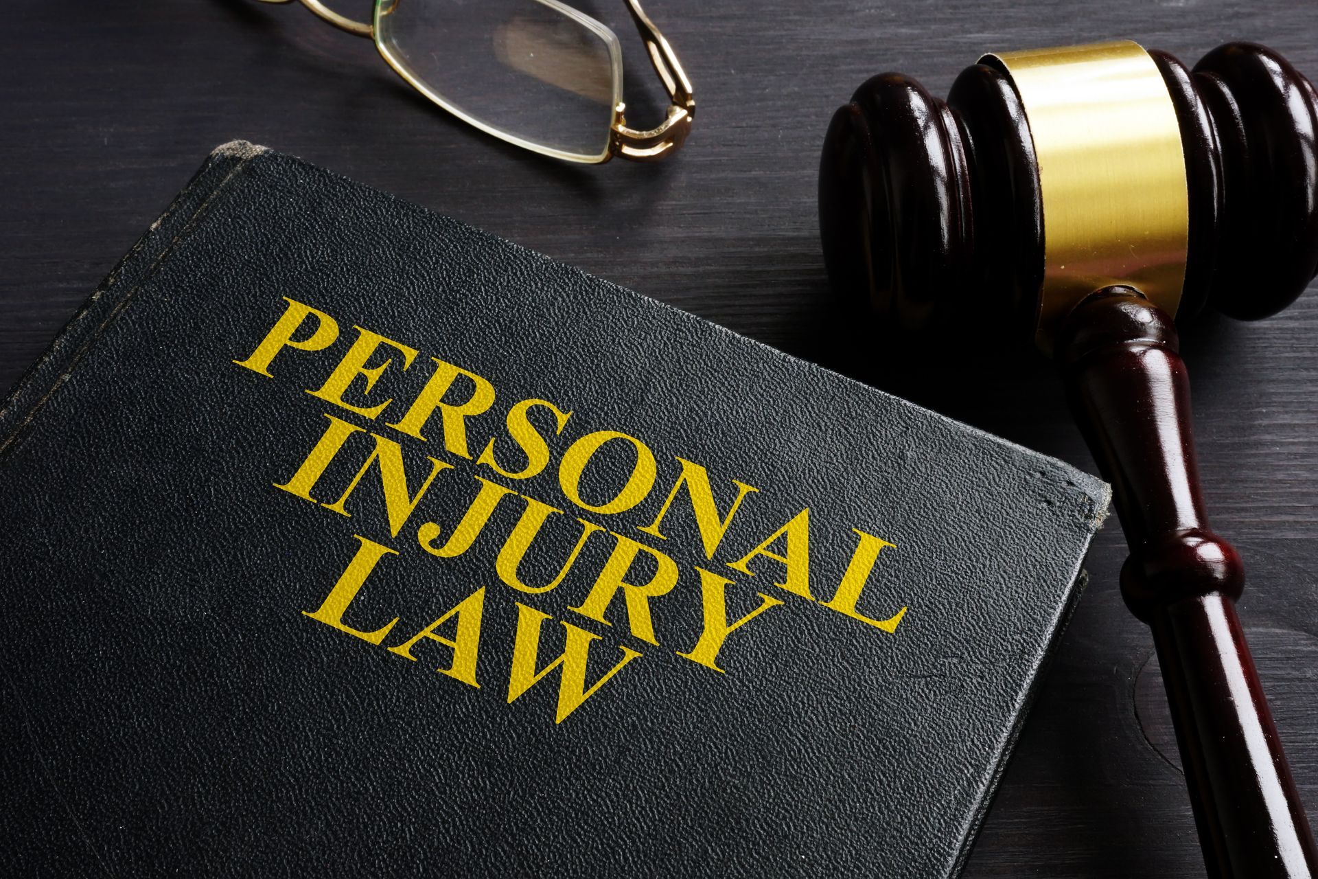 A book titled personal injury law next to a judge 's gavel and glasses.