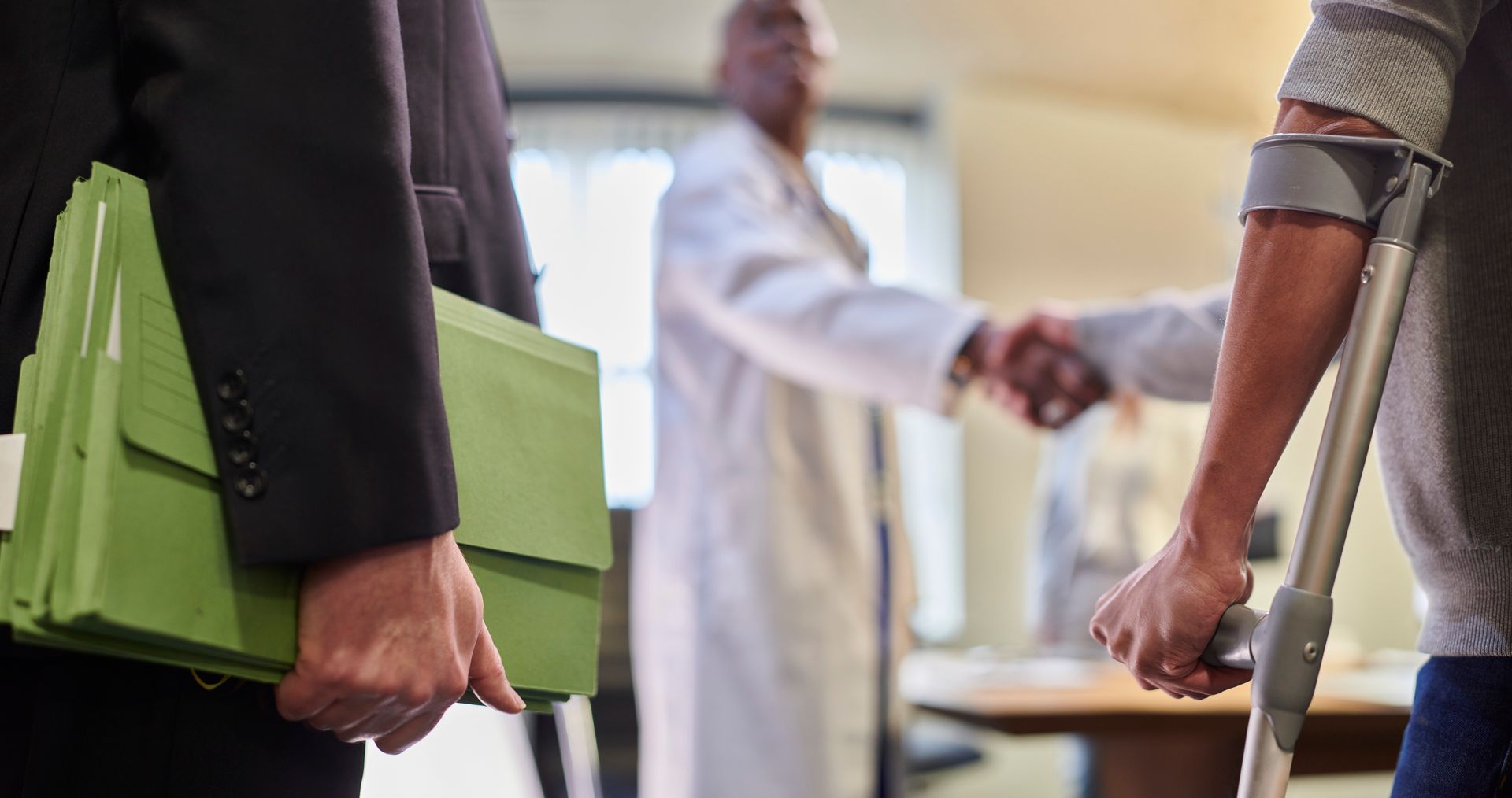A man with crutches is shaking hands with a doctor.