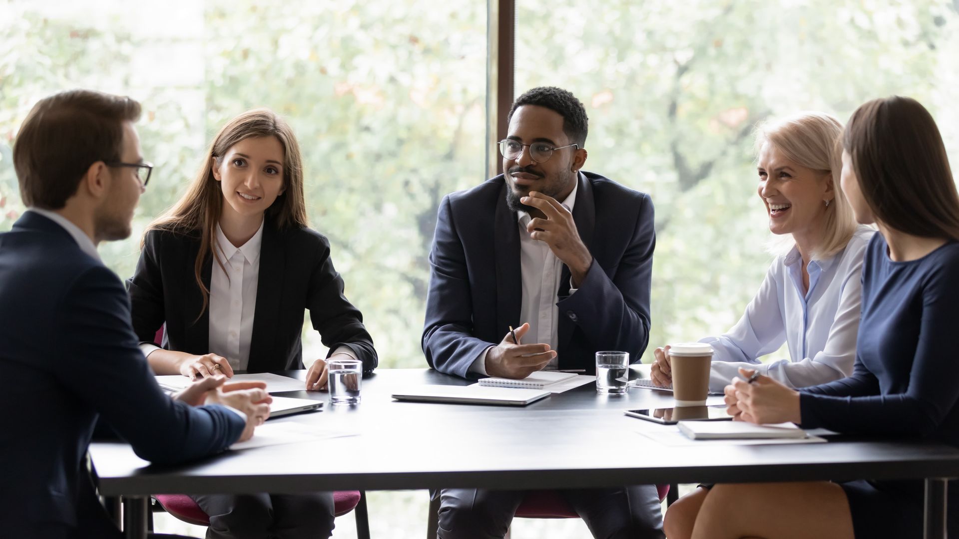 People in a business meeting around a table, listening and discussing in a bright office.