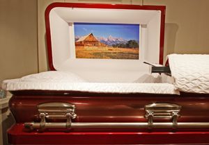 A red coffin with a picture of a house on the inside of it.