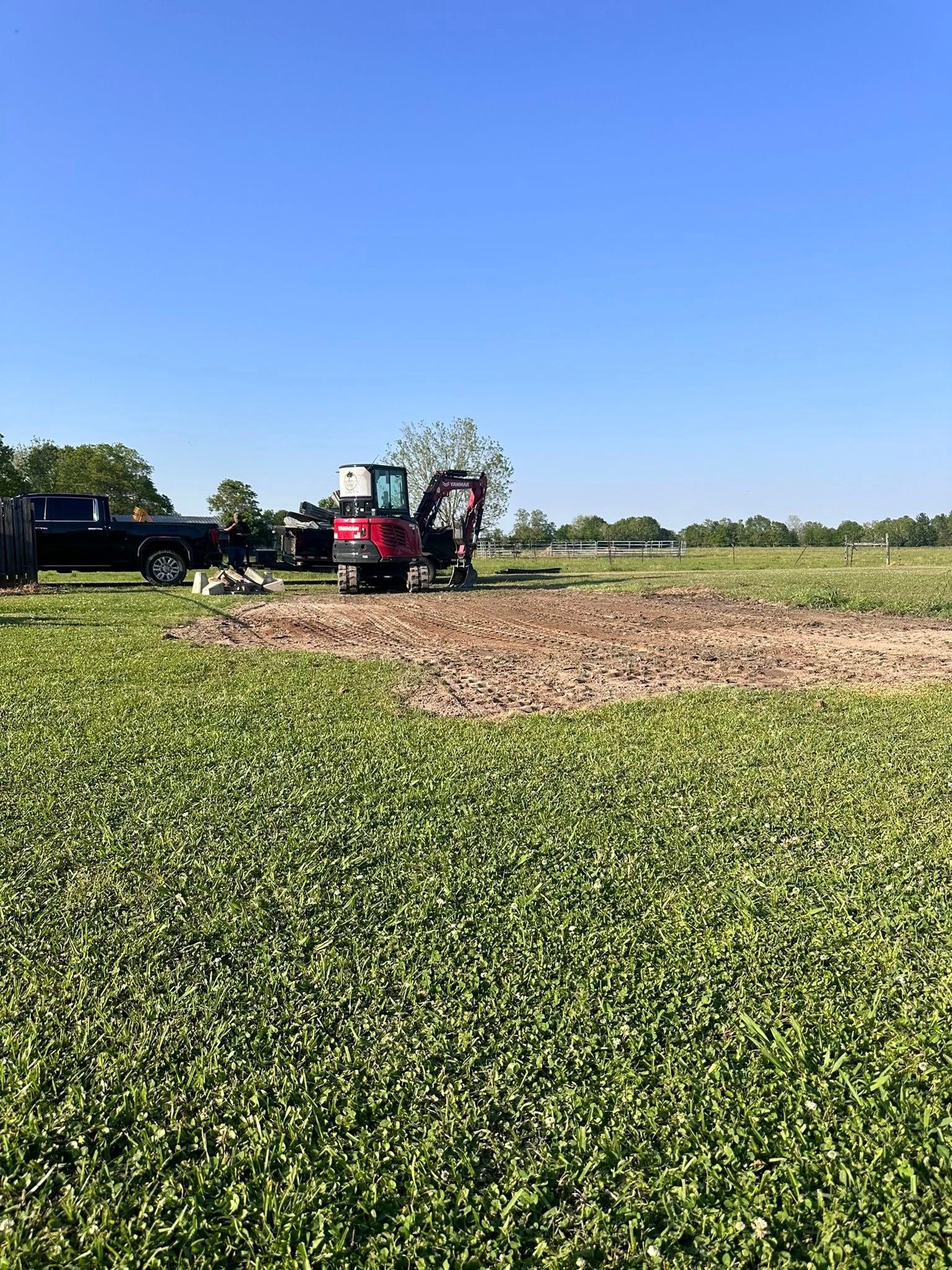 Red tractor working in a green field under a clear blue sky