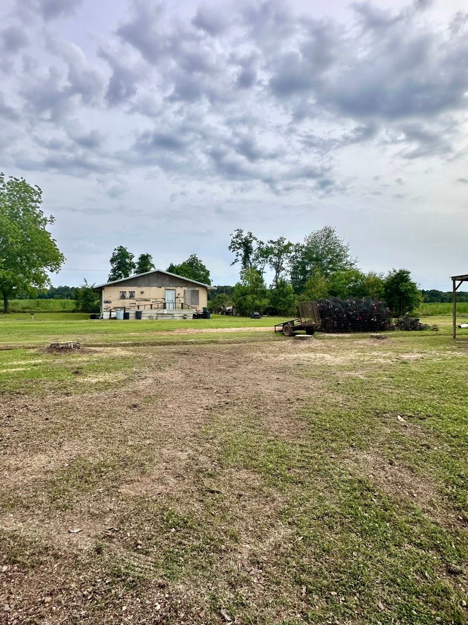 Rural house with a cloudy sky, gravel driveway, and a tractor in the foreground